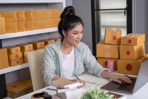 A small business owner sitting in her crowded office checking inventory. 