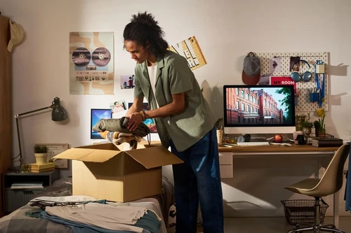 A male student packing up his dorm room into a brown box at the end of the semester.