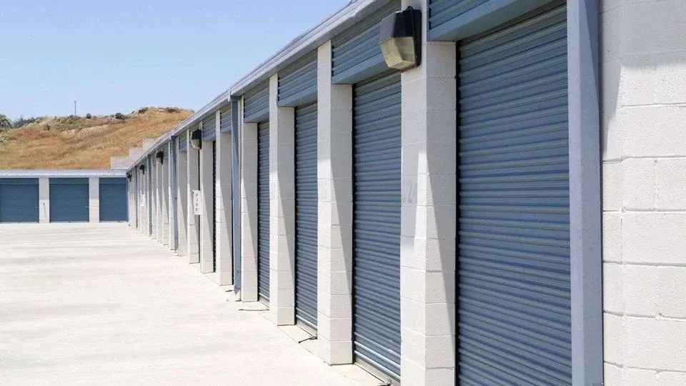 Row of outdoor storage units with large blue doors in a clean area